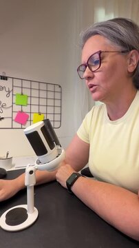 A person shares insights on personal growth while sitting in a home office. The space has a microfono and a whiteboard with colorful notes. It's daytime and well-lit.