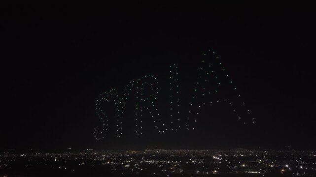 Aerial drone view of a spectacular drone light show spelling the word Syria at night. Illuminated drones forming glowing letters in the dark sky. Aerial entertainment celebrating Syrian heritage. Nigh
