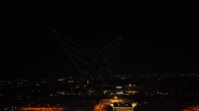 Aerial drone view of a spectacular drone light show spelling the word Syria at night. Illuminated drones forming glowing letters in the dark sky. Aerial entertainment celebrating Syrian heritage. Nigh