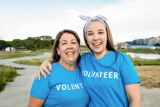 Happy multigenerational volunteers smiling on camera outdoors at park city - Focus on senior woman face
