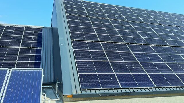 Rooftop solar panels are arranged to capture sunlight in an urban area. They convert sunlight into energy on a sunny day. The clear sky provides good conditions for solar power.