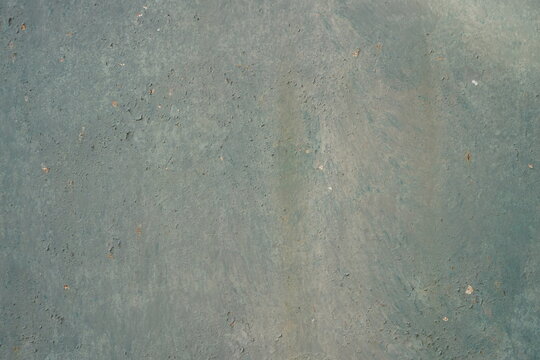 Muted teal green painted metal background with subtle weathered texture closeup. Old iron sheet with faint flaking paint pattern and rust specks, rustic industrial backdrop.