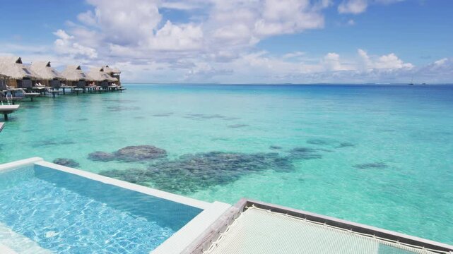 Resort hotel Infinity pool in travel vacation paradise with overwater bungalow in ocean lagoon with coral reef sea. 4K Video from Bora Bora, French Polynesia, Tahiti, South Pacific Ocean. Real video.