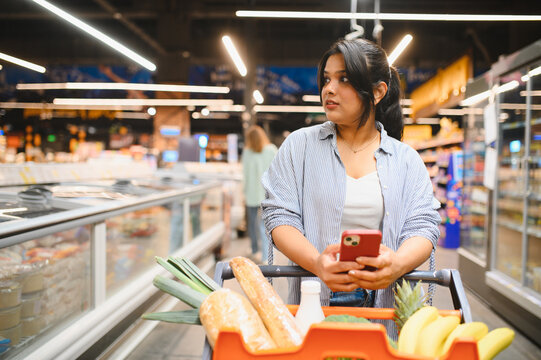 Woman shopping for groceries using smartphone in supermarket