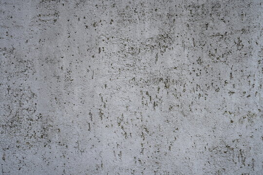 Weathered grey concrete wall texture background closeup. Rough plaster surface with dark pits and grain pattern, rustic minimalist backdrop.