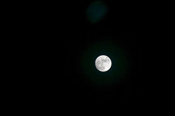 Bright full moon shining in the dark night sky with visible lunar surface details © Holger