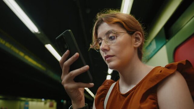 Distracted woman in a subway station uses her phone