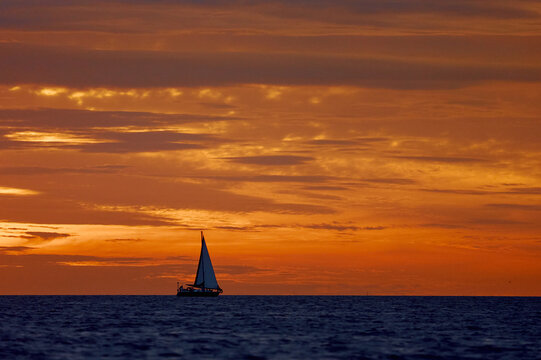 Yachtsmen are sitting amicably on board the boat at incredible sunset, sailing boat is in sailing regatta in the Gulf of Finland, magic splashing water, teamwork, Russia, St.Petersburg