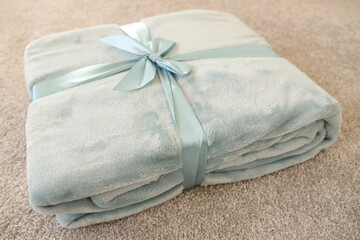 A soft fleece blanket, folded, tied with a blue ribbon. Home textiles, gift, warm accesorry.. © Olga_Burtseva