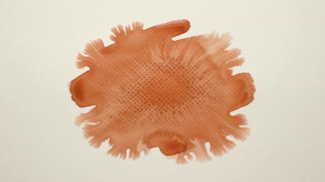 An artistic terracotta watercolor blotch with organic feathered edges on textured cream-colored paper. The earthy orange pigment shows fine details of the paper grain.