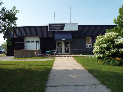Gatineau, Quebec, Canada &ndash; July 02, 2026: A commercial storefront for "D&eacute;panneur Delta" featuring a green metal roof, propane cages, and a parked silver car outside at 411 Bd Saint-Ren&eacute; E.