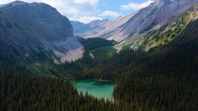 Lillian Lake pristine alpine waters surrounded by dense pine forest and mountain peaks. Kananaskis, Alberta, Canada. aerial view