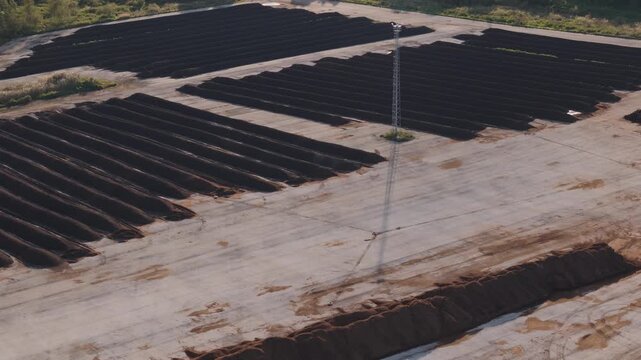 Tallinn, Estonia - September 28, 2025: Aerial footage captures the progression of sewage sludge composting windrows in neat rows on a concrete surface, with vegetation visible in the background.