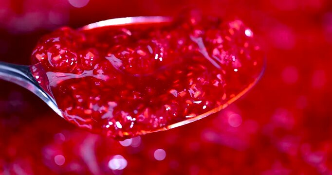 Grated raspberries of bright red color in an iron spoon, sweet grated raspberries with small bones were shot against a blurred background of homemade preparations