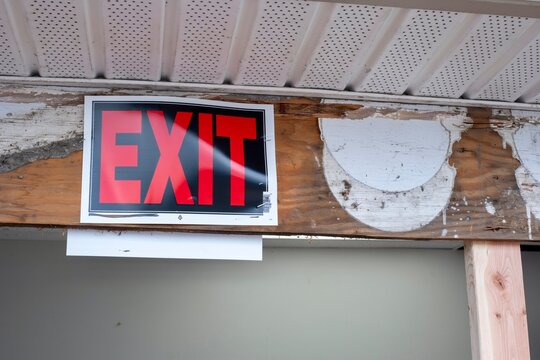 Red exit sign posted on weathered wooden beam