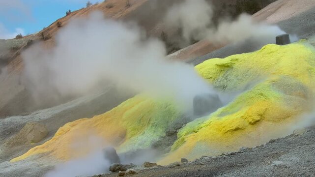 Steam rises from acidic water springs in a geothermal landscape