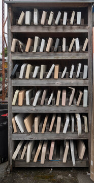 Tank lid Tank cover, Cistern lid-A wooden shelving unit is neatly stacked with rows of various colored ceramic toilet tank lids in a salvage yard.