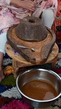 Marrakech, morocco. August 9, 2026. Berber woman manually grinding argan nuts with a stone mill. Traditional moroccan production of cosmetic oil, a liquid gold from morocco