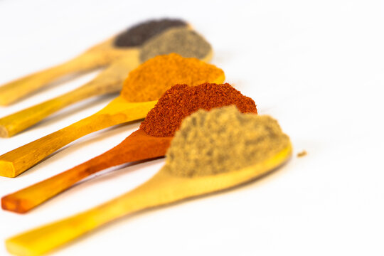 Colorful Indian Spice Powders in Wooden Spoons on White Background