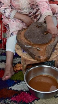 Marrakech, morocco. August 9, 2026. Berber woman using a hand operated stone mill to grind argan nuts, extracting precious oil in a traditional moroccan cooperative