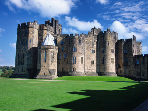 Medieval English Castle with Stone Towers and Green Lawn Under Blue Sky