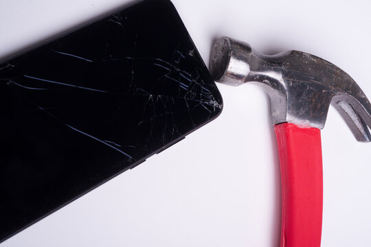 Smartphone with cracked screen. Screen damage. Phone hit by a hammer broken electronics and repair concept. Phone screen shattered by force. Smartphone damage on white background.
