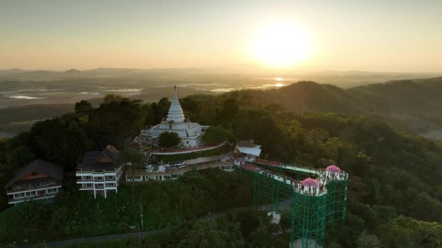 Aerial view of Phra Borommathat Phutthanimit Chedi and skywalk at Wat Phrathat Pha Ngao. The temple complex rises above the forested hillside in year 2023