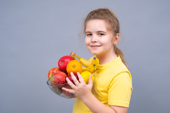 Portrait of child holding vitamin-rich food. Fresh fruits in hands of teen kid. Kid with mix of healthy fruits. Kid holding bowl full of fruits. Healthy lifestyle and kids nutrition concept.