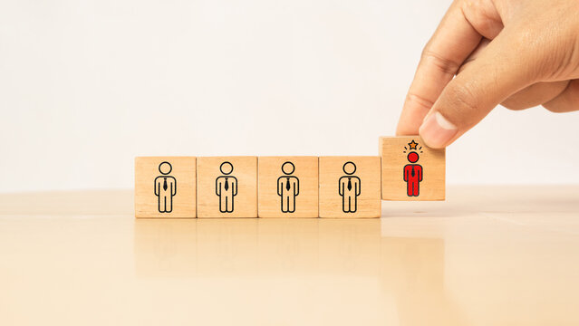 Leadership concept with standout red business person among identical team on wooden blocks representing individuality, talent recognition, human resource selection, professional differentiation