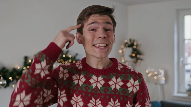 Young man in festive sweater lip syncing with hand gestures dancing. Happy guy celebrating Christmas at home. Joyful holiday vibes with seasonal decor, facial expression