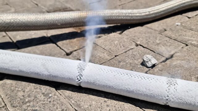 Industrial White Braided Hose Rupture with Pressurized Steam Leak on Pavement