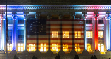 Naklejka premium Building facade with patriotic lights. Building exterior displays freedom banner. Federal architecture frames building flag. Night celebration illuminates building columns.
