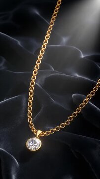 Diamond necklace with a single solitaire pendant resting on draped dark velvet fabric under a top light beam