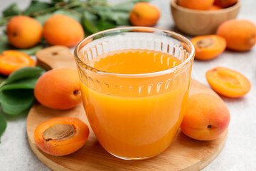 Apricot juice in glass, fresh fruits and leaves on light table, closeup © New Africa