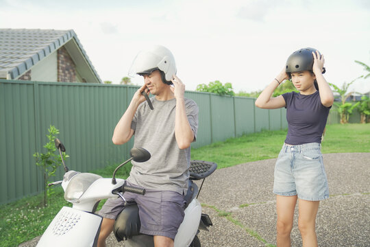 father daughter wearing helmet safety going to ride scooter motorcycle with  family enjoy a sunny day ride together through a  suburban neighborhood 