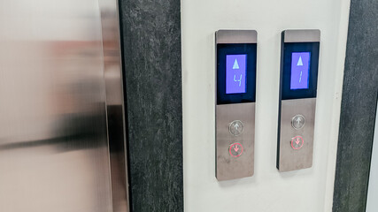 Elevator control panel with two buttons. One button is illuminated blue, indicating upward movement. The panel has a sleek, modern design. © Екатерина Говорина