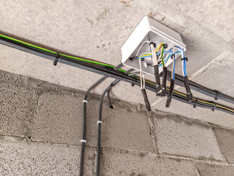 Electrical junction box mounted on a concrete wall with multiple wires connected. The scene shows a close-up of the wiring setup in a building.