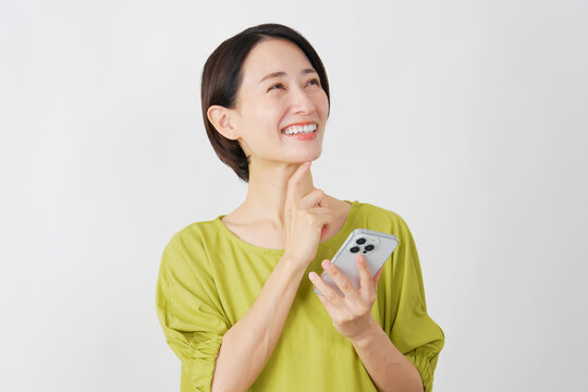 スマホを持って想像するミドル女性　白背景