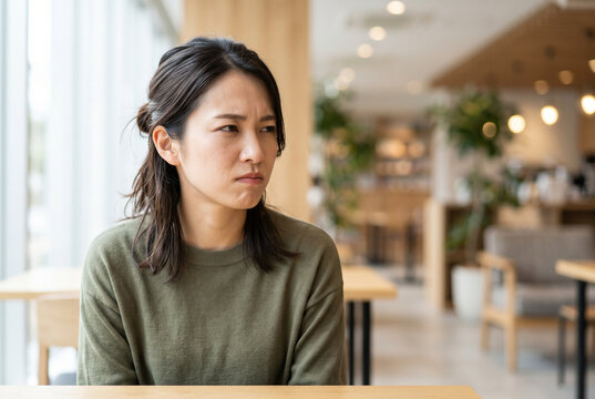 カフェで不満げな表情を浮かべる日本人女性 Generative AI