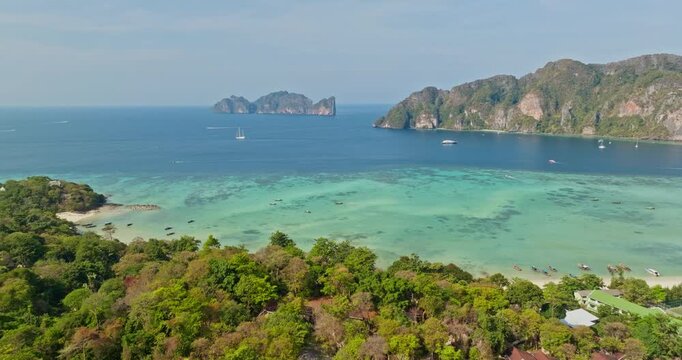 Lush green trees framing scenic panoramic view of Phi Phi Don and Phi Phi Leh in Andaman Sea, turquoise water, coral reefs and limestone karsts. Thailand travel tourist destination. Aerial view flight