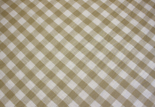 Texture of crumpled gold and white gingham linen like cloth. Close up of wrinkled diagonal ocher plaid fabric background. 