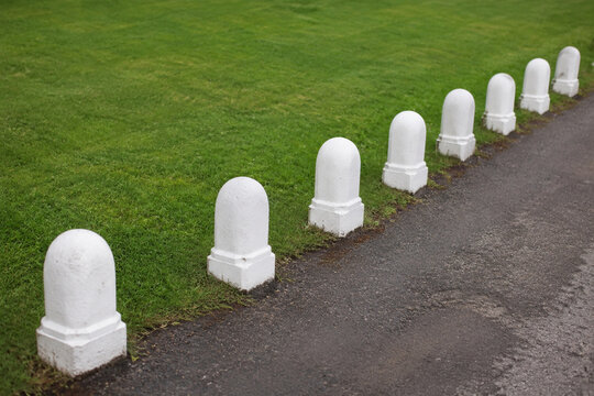 Row of white stone bollards and manicured lawn, boundary and landscaping concept
