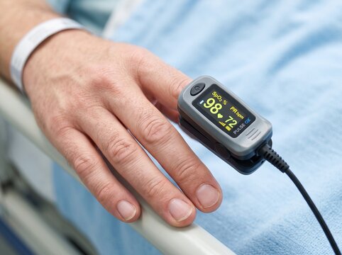 Patient finger inside a digital pulse oximeter device measuring blood oxygen level with oximeter healthcare hospital monitoring measurement clinical treatment emergency