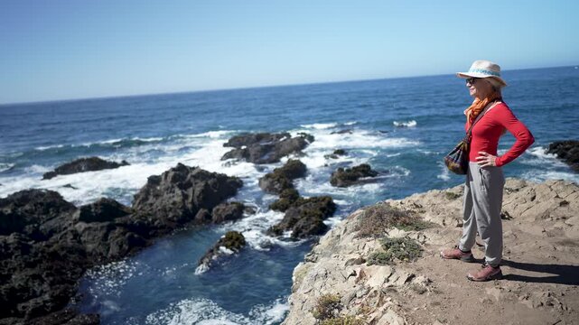 Mature woman hikes along headlands at Mendocino Coast Botanical Gardens while exploring ocean views and coastal flora in California.