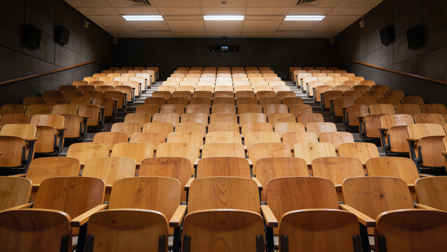 Tiered wooden lecture hall with rows of chairs in ascending formation, empty academic venue