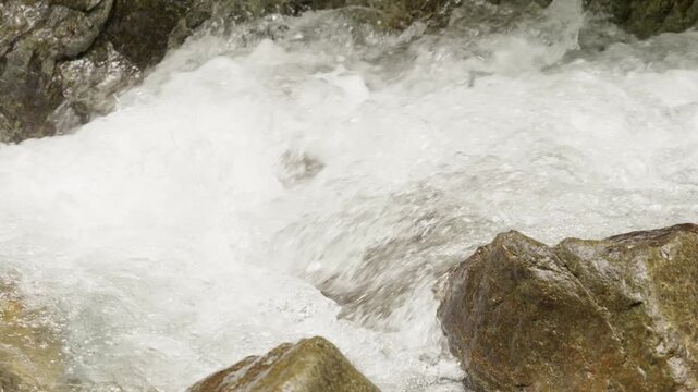Rushing stream cascading over rocks in the mindo nambillo forest, captured in slow motion