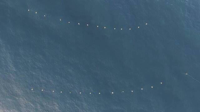 Aerial view over Ocean with bouys marking a jetty entrance bobbing on the waves