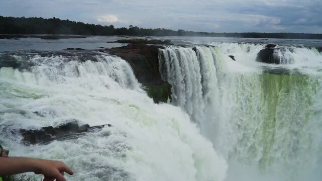 A hand pointing toward the powerful Devils Throat waterfall at Iguazu in slow motion