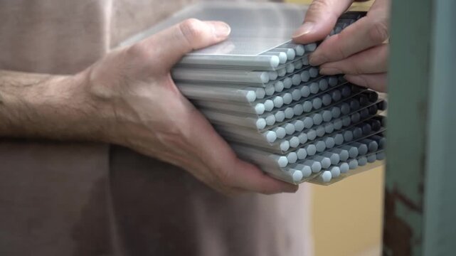 Hand holding a bundle of finished colored pencils with sharpened tips at a factory