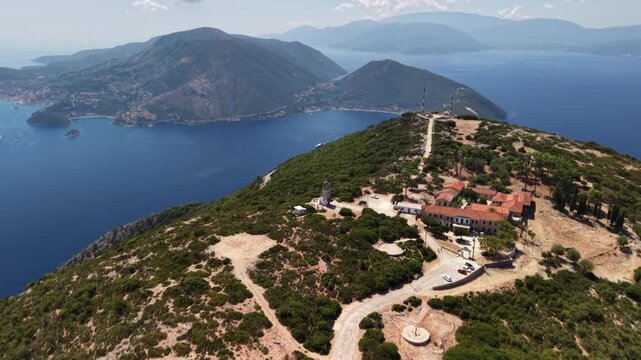 Stunning drone rotate around Kathara Monastery from far, revealing Vathy bay, Ithaca, Greek Islands